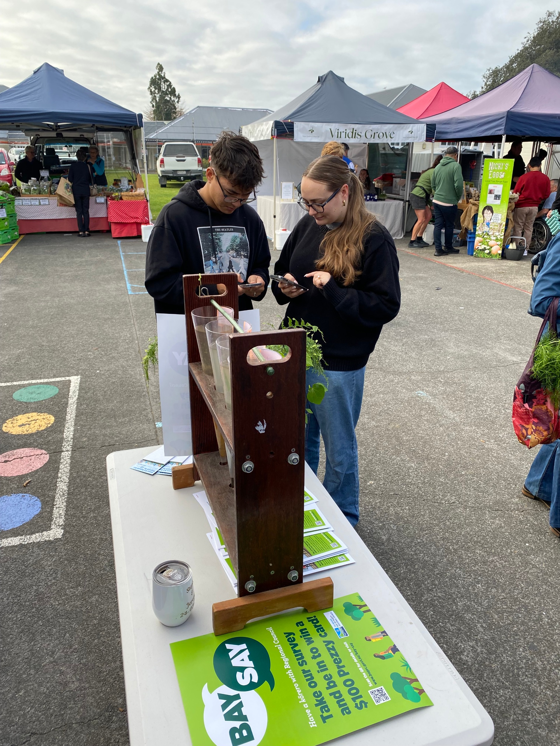 Two young people looking at water samples at a market